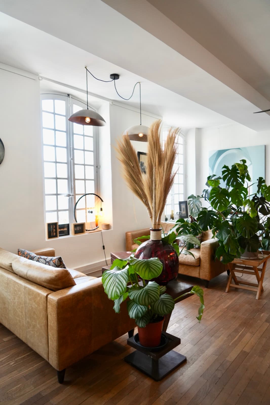 Le salon de la maison : canapés en cuir, plantes et volumes anciens