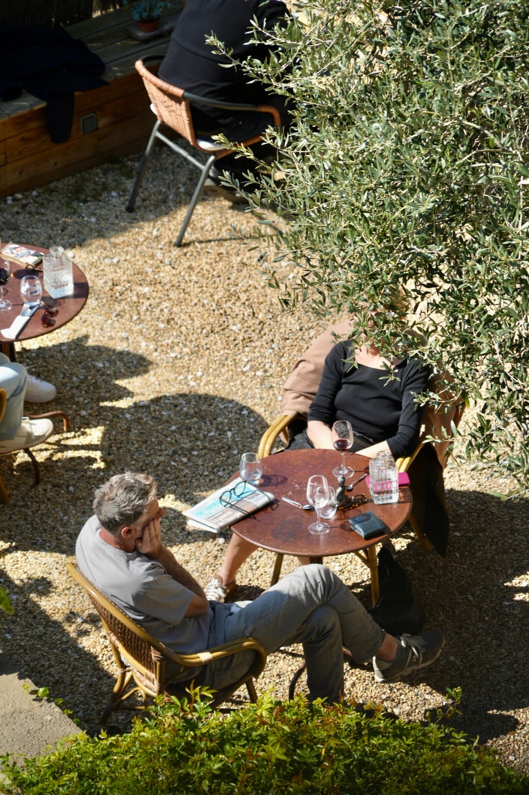 Des convives attablés dans le jardin caché, sous l'olivier